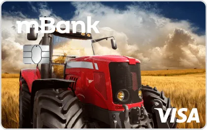 Czerwony traktor na polu. Traktor jest duży, solidny, z dużymi kołami przystosowanymi do pracy na roli. Kabina traktora jest zamknięta. W tle widać łany zbóż i niebo
