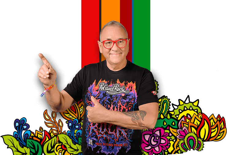 Uśmiechnięty Jurek Owsiak w koszulce Pol'and'Rock Festival wskazujący palcem w górę, obok baner z informacją o Akademii Sztuk Przepięknych