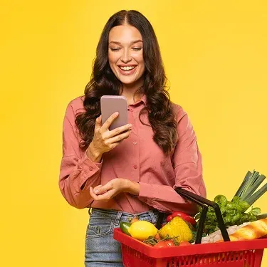 Kobieta z koszykiem zakupów Biedronki korzystająca z telefonu