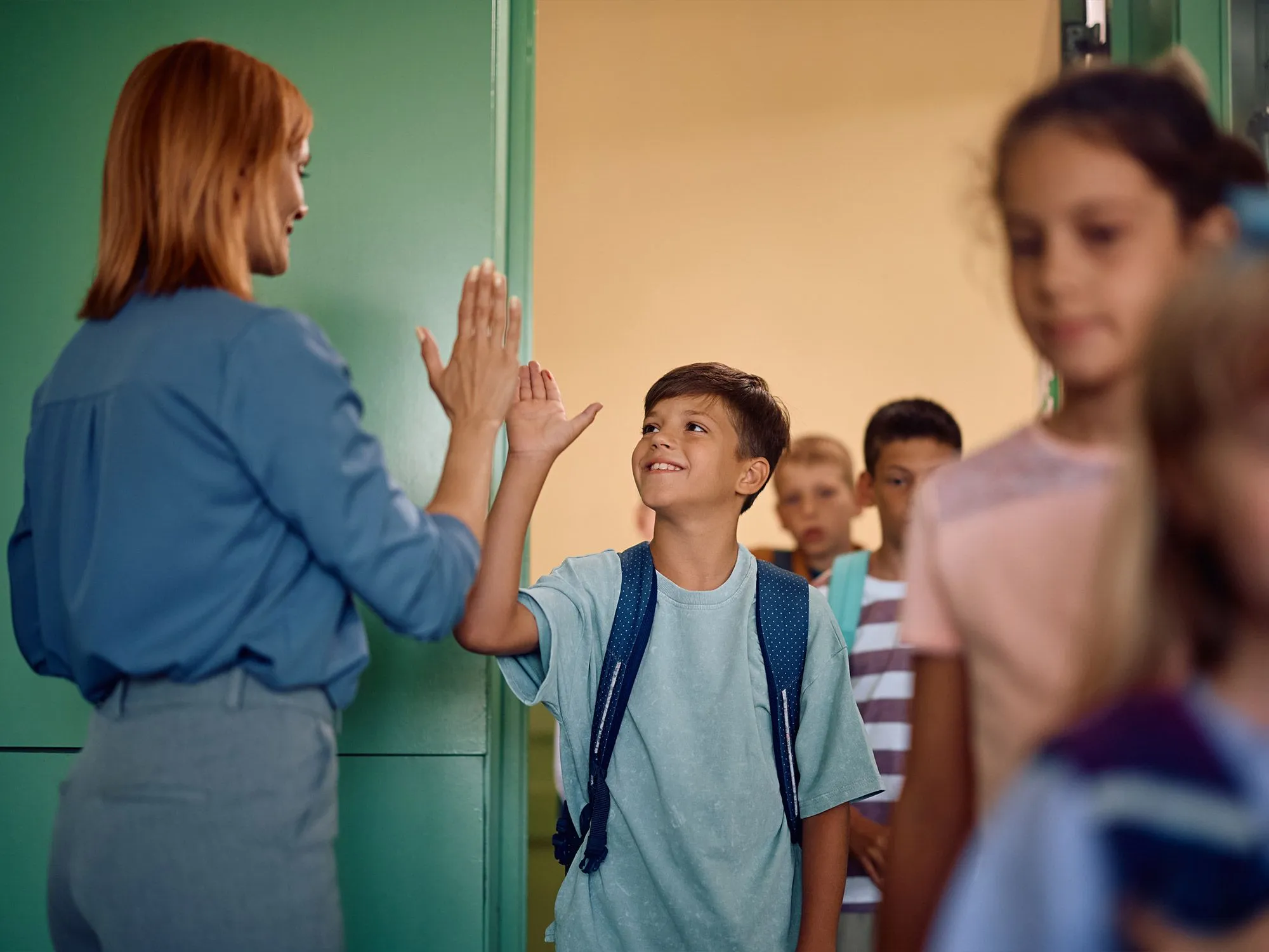 nauczycielka w otoczeniu grupy uśmiechniętych dzieci w szkolnej sali