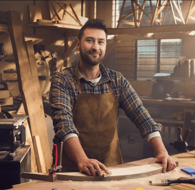 Mężczyzna w koszuli w kratę, uśmiechnięty, właściciel warsztatu stolarskiego. Widoczne logo mBanku i hasło „Załóż firmę i zyskaj konto za 0 zł na zawsze aby cieszyć się sukcesem we własnej firmie